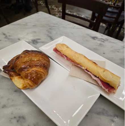 Croissant y mini flauta de jamón sobre mesa de mármol